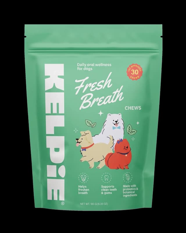 A green pouch of dog treats labeled Kelpie Fresh Breath Chews, featuring an illustration of two dogs, with text indicating fresh breath support, clean teeth and gums, and natural ingredients.